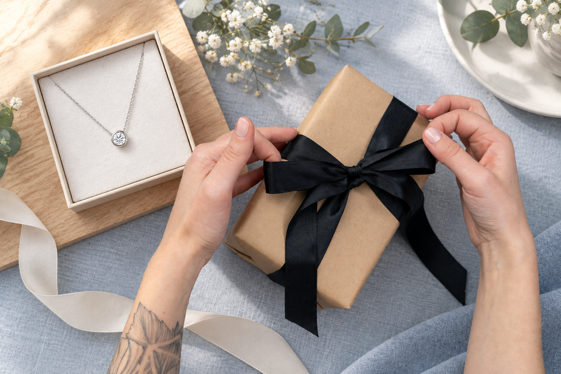 贈り物を包む手元と覆輪留めの一粒ネックレスを組み合わせたイメージ